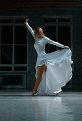 Fototapeta na wymiar a girl in a white dress with a bared beautiful leg looks down, contemporary in a ball gown image.