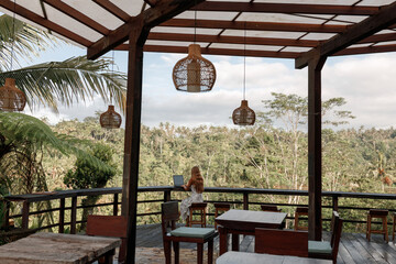 Freelance concept. Pretty young woman using laptop in cafe on tropical beach in outdoor cafe terrace. Work and travel