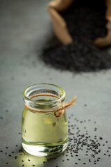 Sesame oil and raw black sesame seeds on dark background