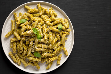 Homemade Pesto Twist Pasta on a plate on a black background, top view. Overhead, from above, flat lay. Copy space.