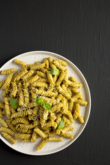 Homemade Pesto Twist Pasta on a plate on a black background, top view. Overhead, from above, flat lay.