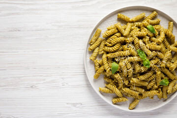 Homemade Pesto Twist Pasta on a plate on a white wooden background, top view. Overhead, from above, flat lay. Space for text.