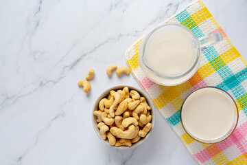 Vegan cashew milk in glass with cashews nuts on marble background