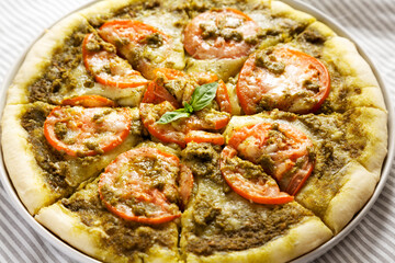 Homemade Pesto Pizza with Fresh Tomatoes and Mozzarella on cloth, side view. Close-up.