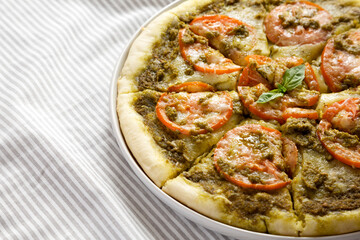 Homemade Pesto Pizza with Fresh Tomatoes and Mozzarella on a black background, low angle view. Space for text.