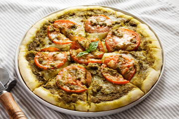 Homemade Pesto Pizza with Fresh Tomatoes and Mozzarella on cloth, low angle view. Close-up.