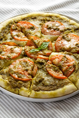 Homemade Pesto Pizza with Fresh Tomatoes and Mozzarella on cloth, side view. Close-up.