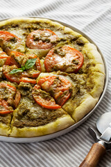 Homemade Pesto Pizza with Fresh Tomatoes and Mozzarella on a black background, low angle view. Close-up.