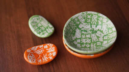 Set of empty green and orange ceramic dishes and stands for sushi sticks on wooden background