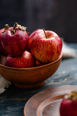 Fresh red apples on a plate on a wooden background. Red apples on a dark background. Selective focus