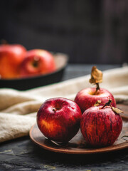 Fresh red apples on a plate on a wooden background. Red apples on a dark background. Selective focus