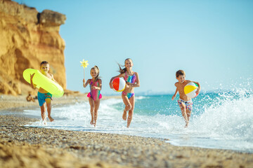 A group of children have fun playing at the sea. Children in bathing suits. Friends holding hands and running on the beach. High quality photo.