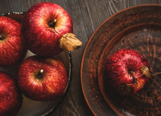 Fresh red apples on a plate on a wooden background. Red apples on a dark background. Selective focus