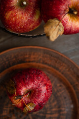 Fresh red apples on a plate on a wooden background. Red apples on a dark background. Selective focus