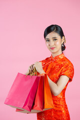 beautiful Asian woman happy smile and shopping in chinese new year on pink background.