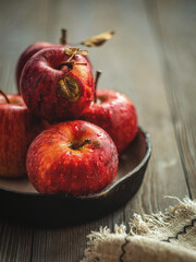 Fresh red apples on a plate on a wooden background. Red apples on a dark background. Selective focus