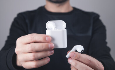 Caucasian man holding white wireless earphones.