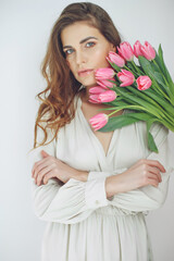 Beautiful woman with tulips. Spring bouquet in the hands of a young and happy girl. High quality photo.