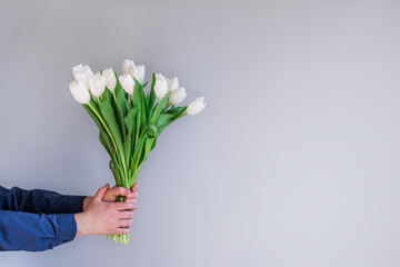 Man holding bouquet of beautiful spring white tulips. Flowers to gift. Place for text.