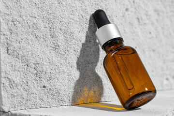 Glass jar of skincare serum on concrete block