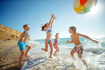 A group of children have fun playing at the sea. Children in bathing suits. Friends holding hands and running on the beach. High quality photo.