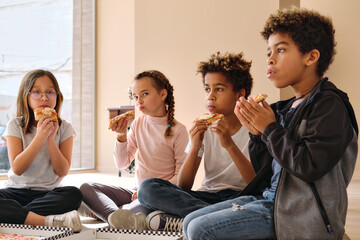 Four little multiethnic boys and girls eating pizza