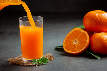 Fresh orange juice in the glass on dark background