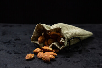Almonds on a black background. Isolated almonds. Roasted almonds pouring out of the bag