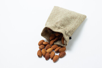 Almonds on a white background. Isolated almonds. Roasted almonds spilled out of the bag