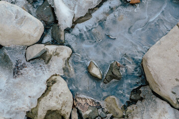 Winter mountain stream among rocks and stones