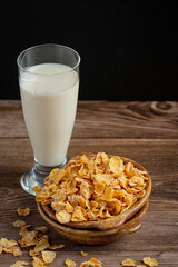 Cereal in bowl and milk on dark wooden background