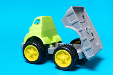 Toy truck car on a blue background - construction equipment for children. Bright children's plastic toys, dump truck childhood. Copyspace banner place for text.
