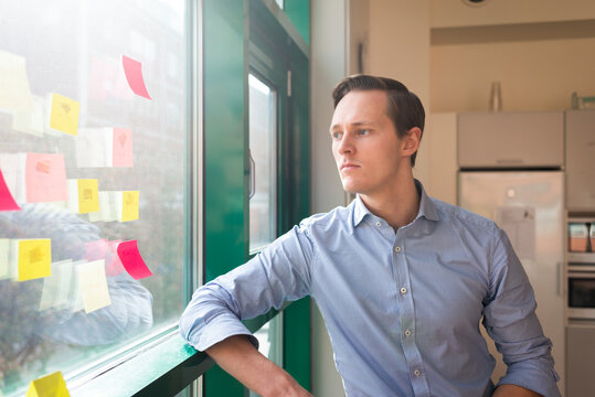 Man looking at notes sticker on window