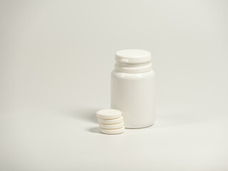 A round white pills and plastic container on the light background