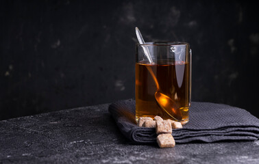 Selective focus: Ceylon black tea in a transparent mug on a dark background. copyspace. horizontal position. minimalistic style