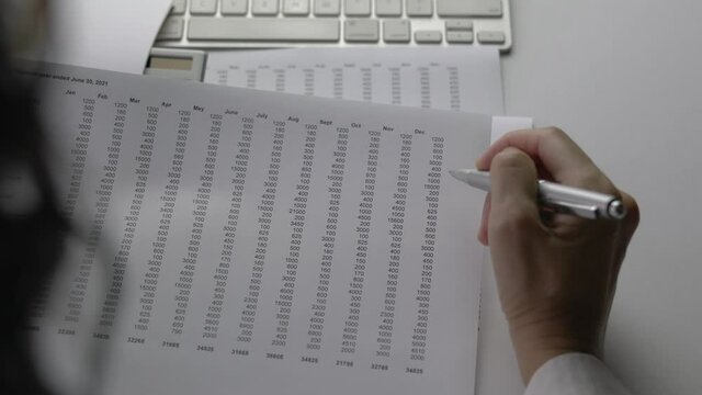 Accountant analyzing data and numbers printed on spreadsheet format. Corporate finance and money accounting concept.