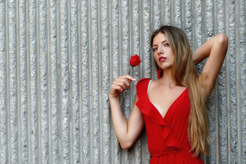 Bellissima ragazza bionda con fiore rosso  - obrazy, fototapety, plakaty
