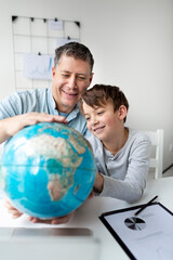 Father learns with child concept. Dad and son get to know the world using a globe.