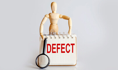 Wooden man shows with a hand to white notepad with text DEFECT