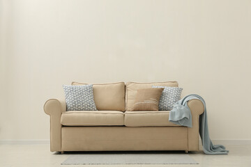 Comfortable sofa near beige wall in living room interior. Space for text