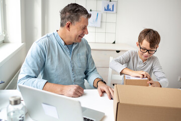 Online shopping concept. Dad and son open a package from an online company during corona crisis.