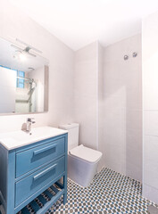 Clean bright bathroom interior with mosaic floor and blue furniture. Original designed space with modern pieces