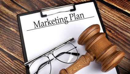 Paper with MARKETING PLAN with gavel, pen and glasses on the wooden background