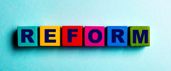 The word REFORM is written on multicolored bright wooden cubes on a light blue background