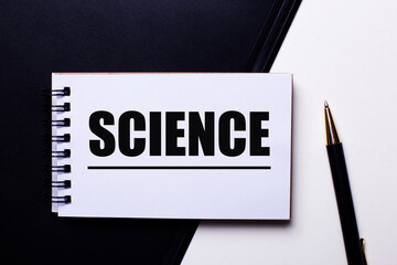 The word SCIENCE written in red on a black and white background near the pen