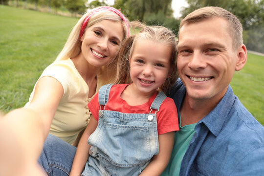 Happy family taking selfie in park on summer day