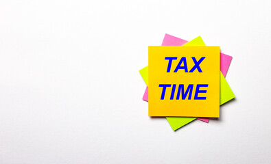 On a light background - bright multicolored stickers with the text TAX TIME. Copy space