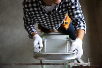 Professional constructor on ladder in old building, top view