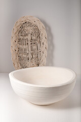 Basket wicker light, with a wooden bowl on a light background with shadows and