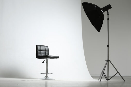 Modern chair and professional lighting equipment in photo studio